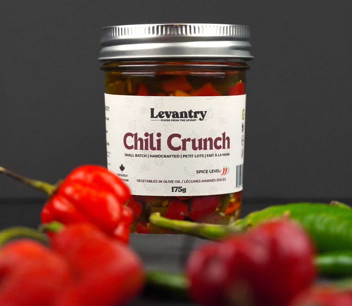 Jar of Levantry Chili Crunch with chili peppers on a dark background